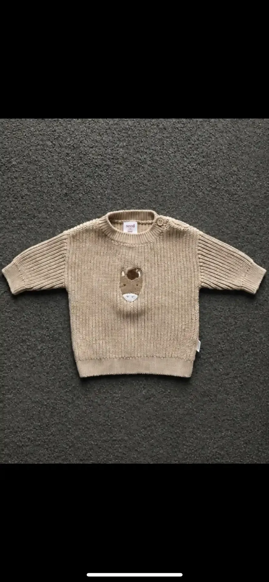 Baby cardigan on dark textured floor before AI styling
